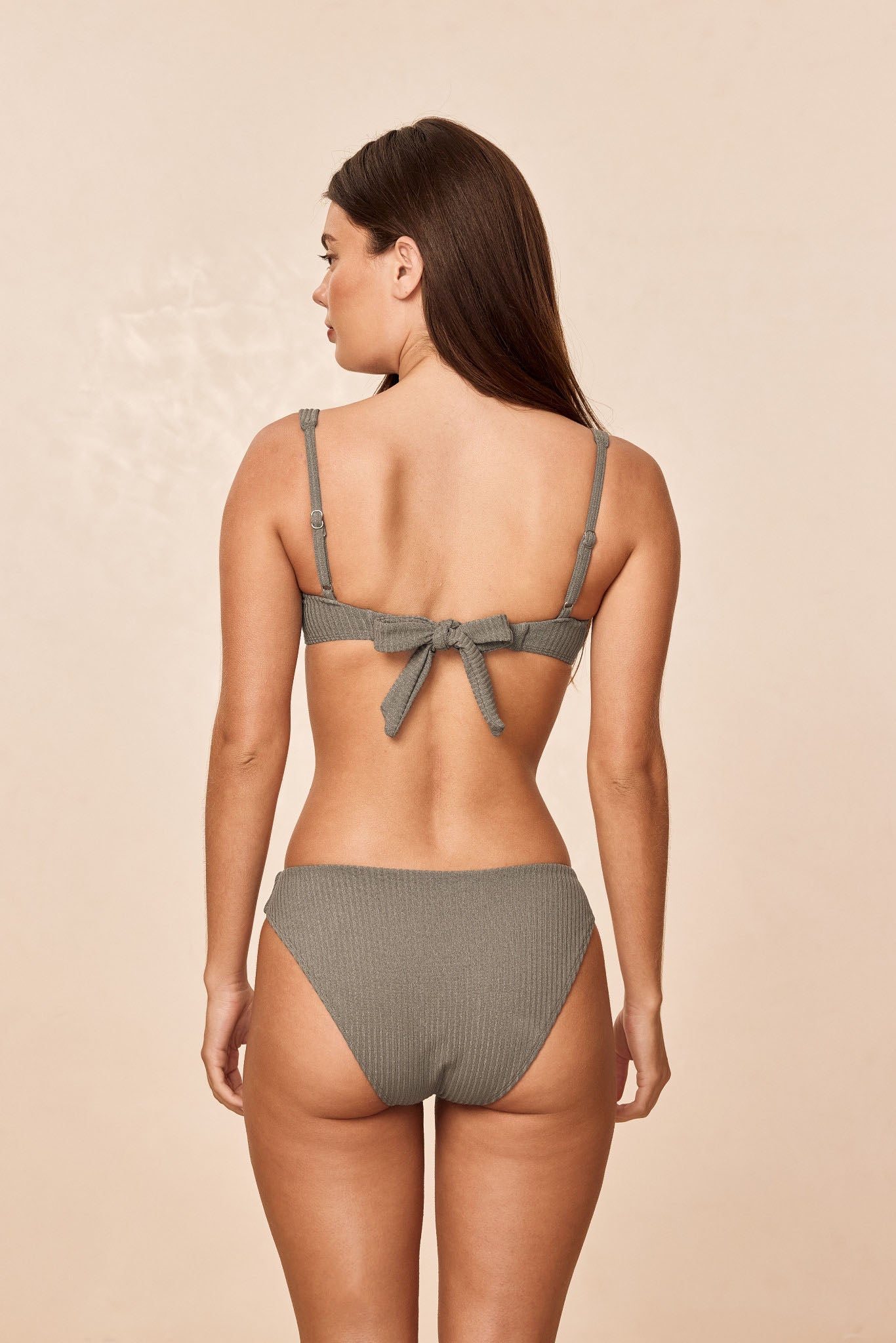Rear view of Sorrento Top in Steel Lurex Rib showcasing tied back bow and adjustable shoulder straps on beige background