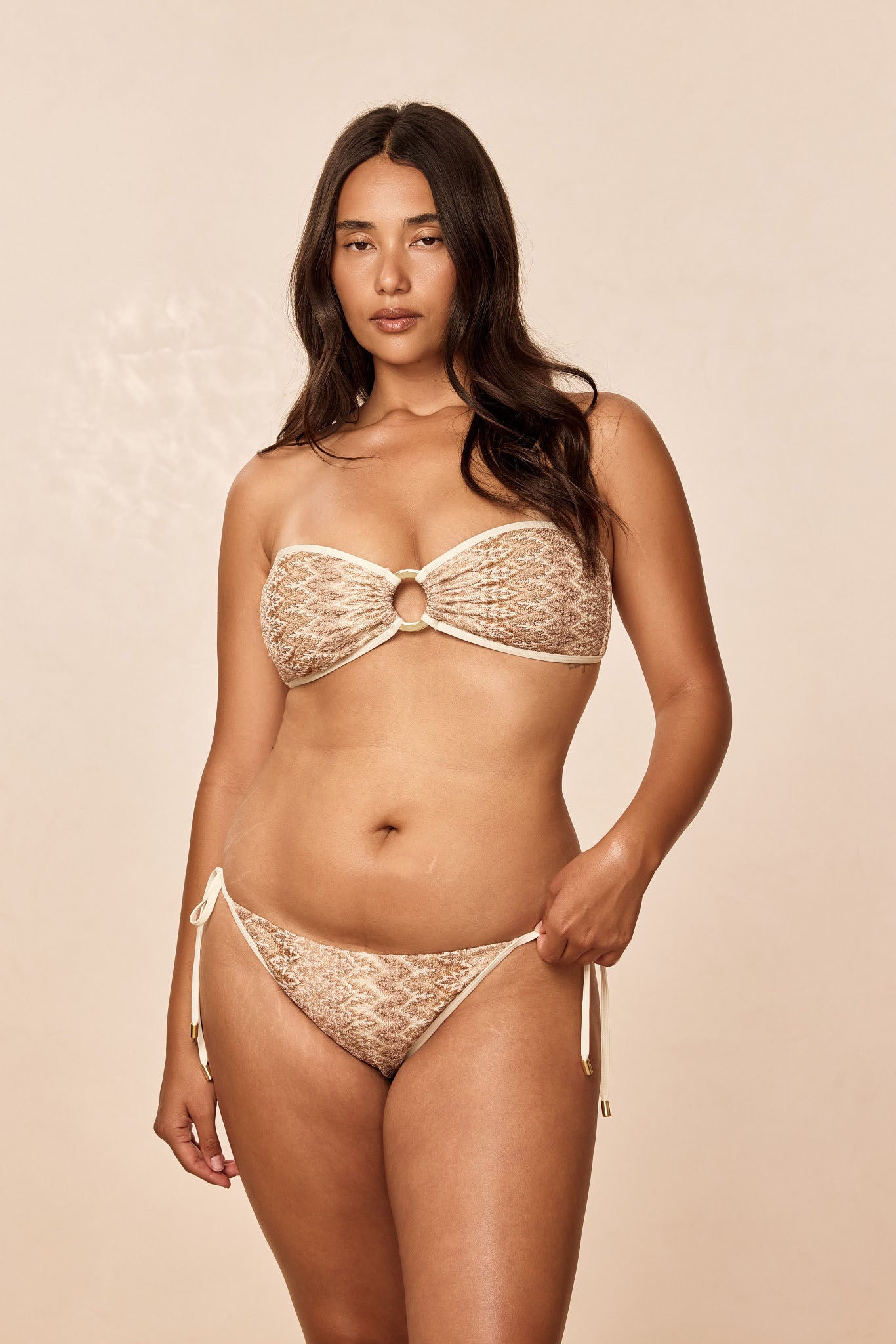 Front view of Le Marais Bottom in Porto Cervo Gold showing textured knit, metal ring and side ties on beige background