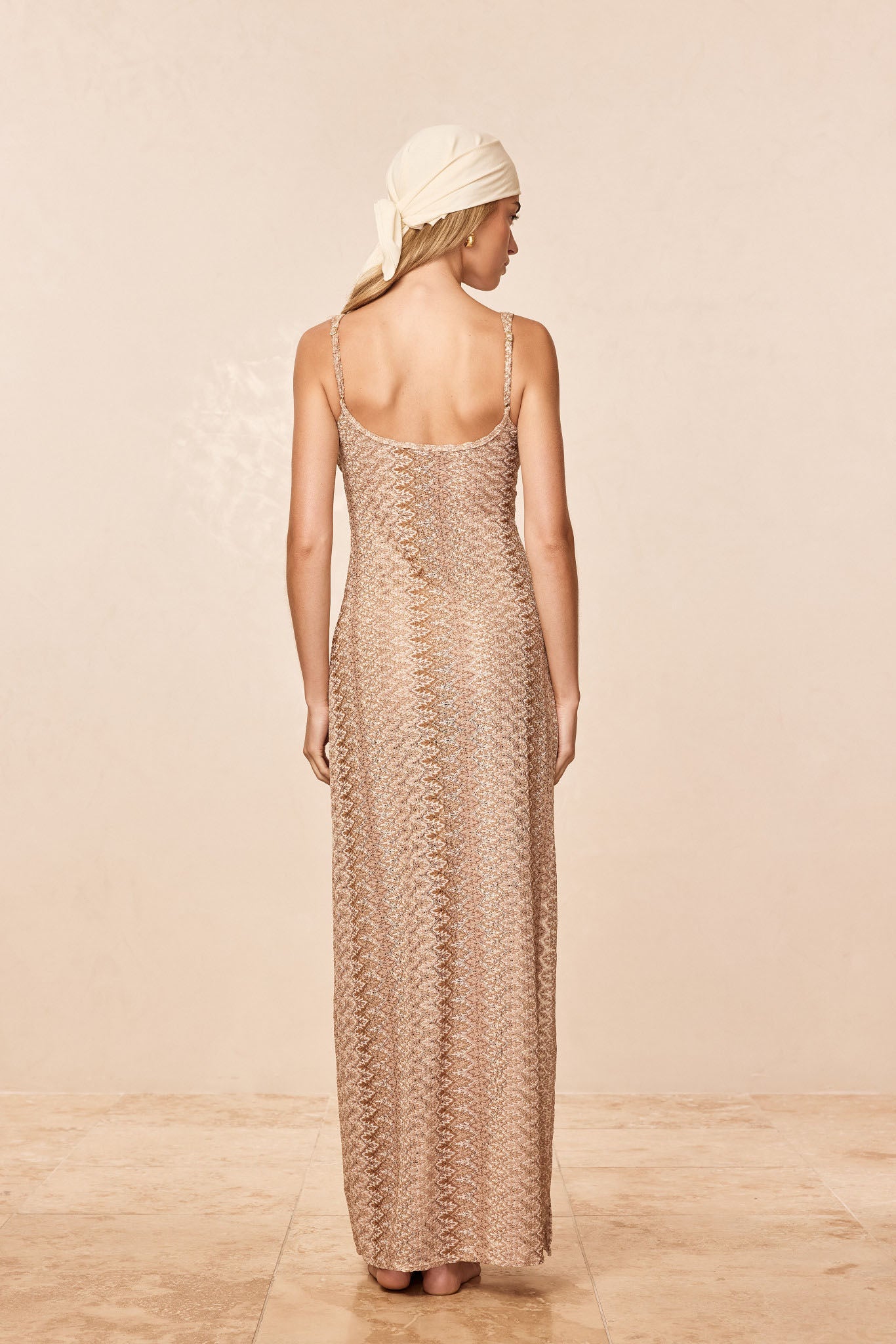 Back view of Sayulita Dress in Porto Cervo Gold showing fitted crochet knit and adjustable thin straps on beige background