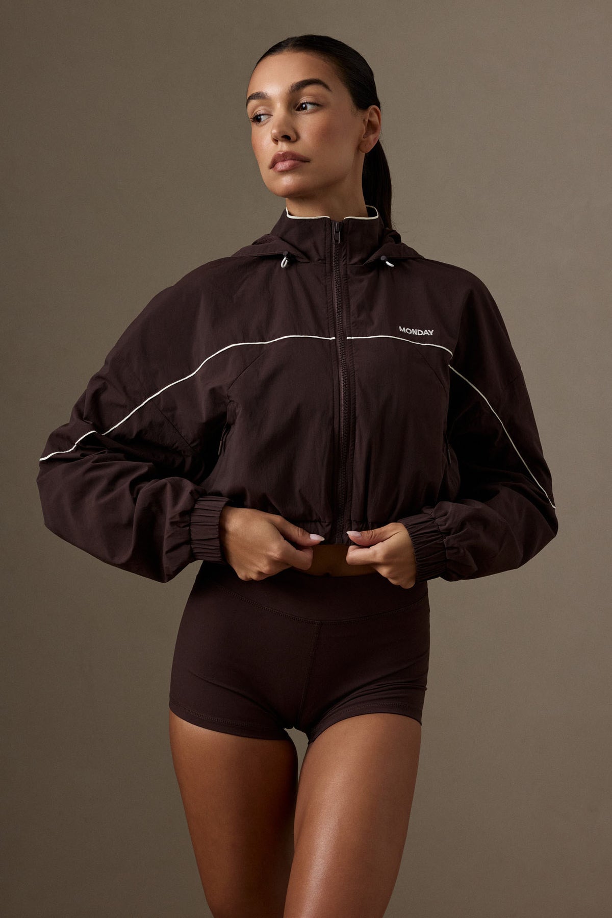 Front view of the Espresso nylon Westmount Jacket showcasing cropped fit, hood, and contrast piping on a model in a studio