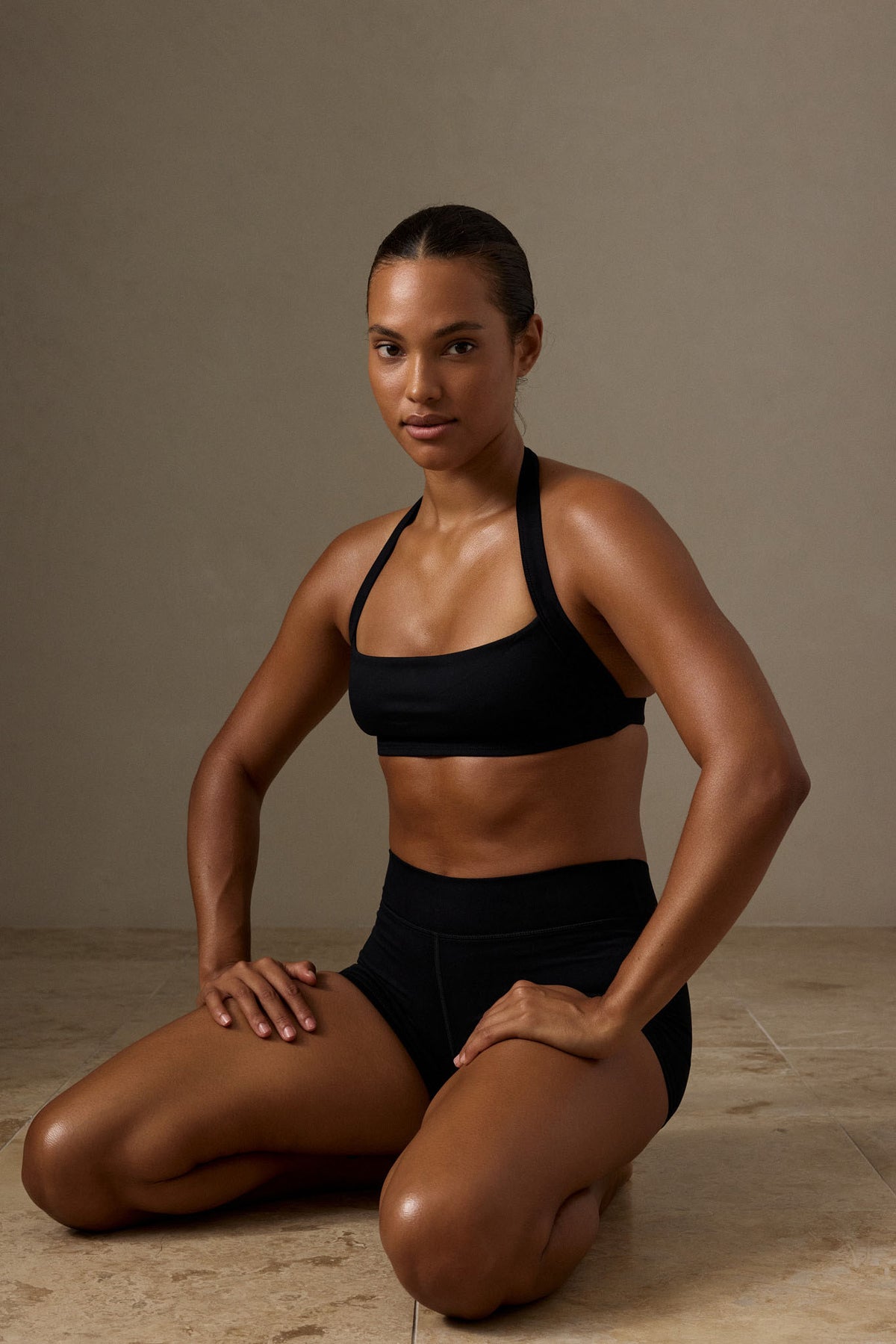 Front view of black Tribeca Halter Bra showcasing its wide halter design on a seated model in a neutral studio