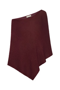 Angled view of Dominica poncho in deep burgundy treble knit with draped hem on white background