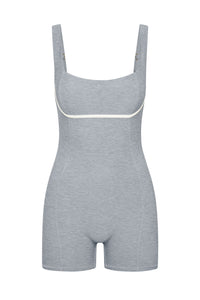 Light-gray shaping bodysuit with shorts, adjustable straps and white piping under the bust.