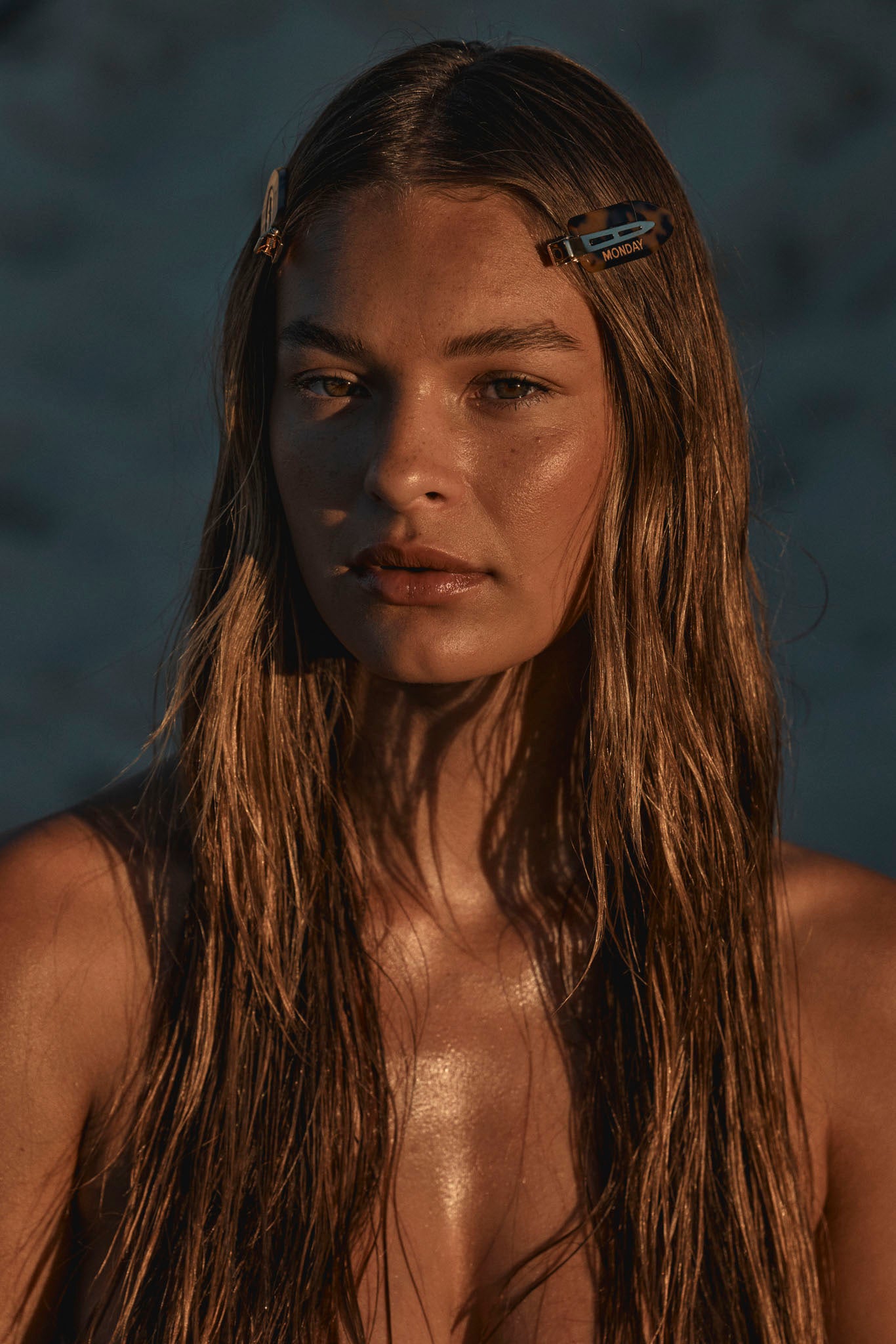 Portrait of a young woman with wet long hair and two hair clips, one reading MONDAY.