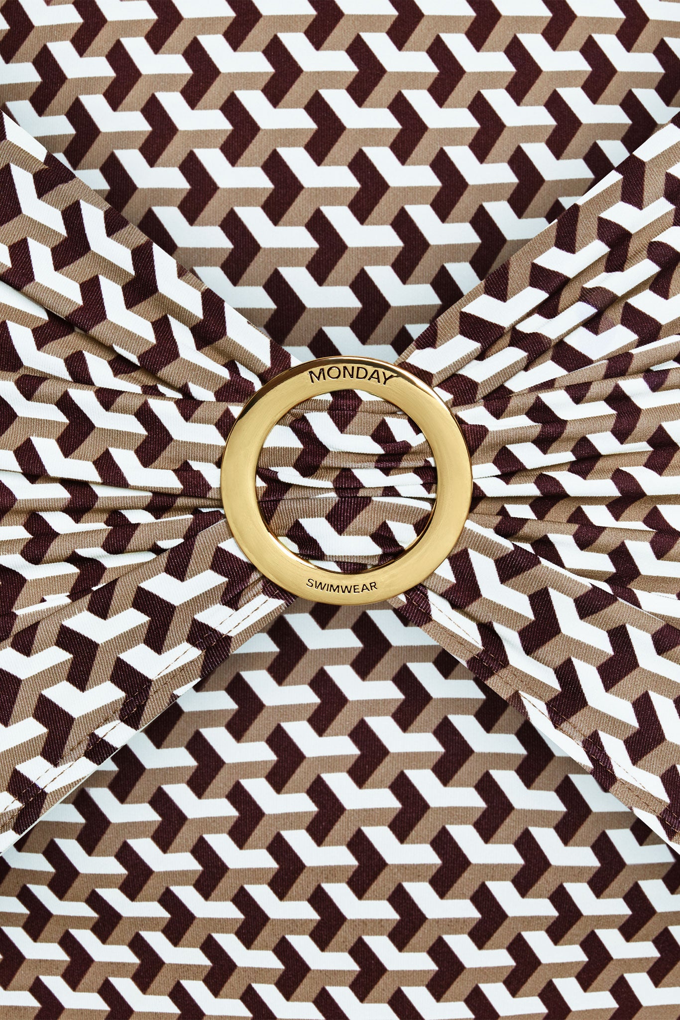Brown, tan and white geometric swim fabric gathered through a gold ring engraved MONDAY and SWIMWEAR.