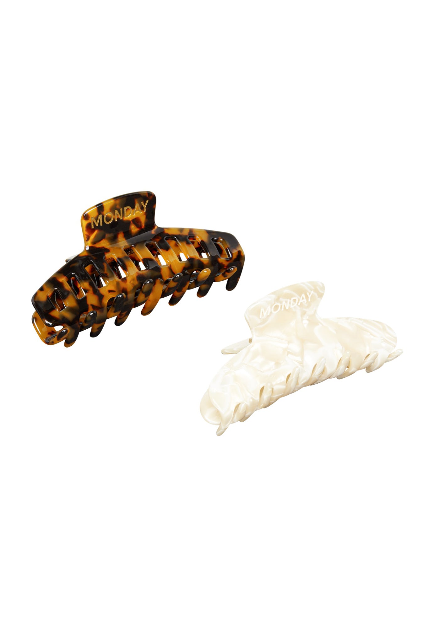 Two hair claw clips — tortoiseshell and pearlescent cream, each embossed with the word MONDAY