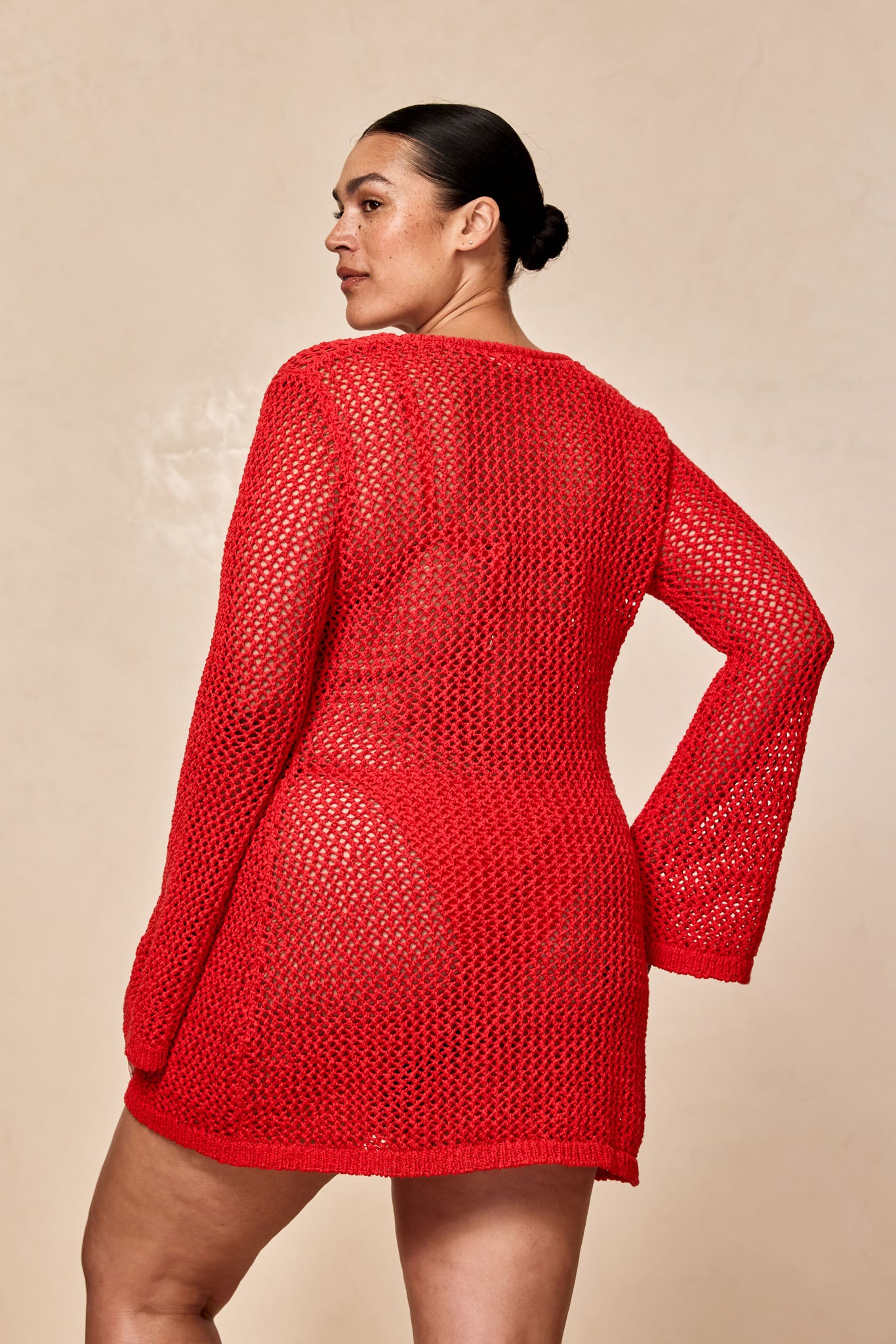 Model back view wearing a red open-knit long-sleeve swim cover-up over a bikini