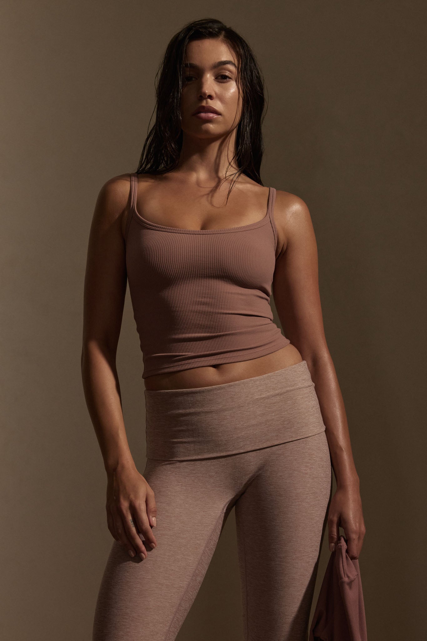 Model wearing mauve thin-rib Devin tank top paired with mauve high-waist leggings, holding matching jacket