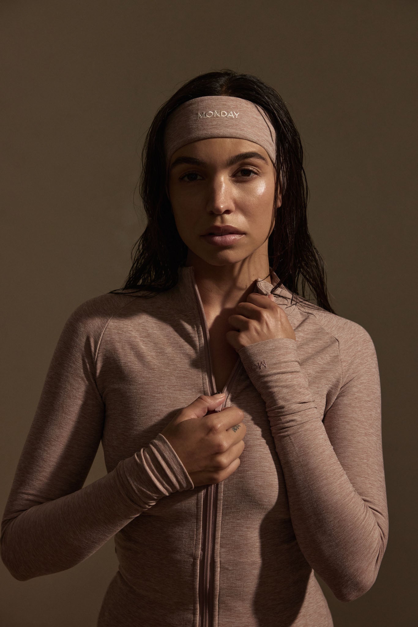 Model wearing heather mauve zip jacket with thumbholes and matching headband embroidered 'MONDAY'.