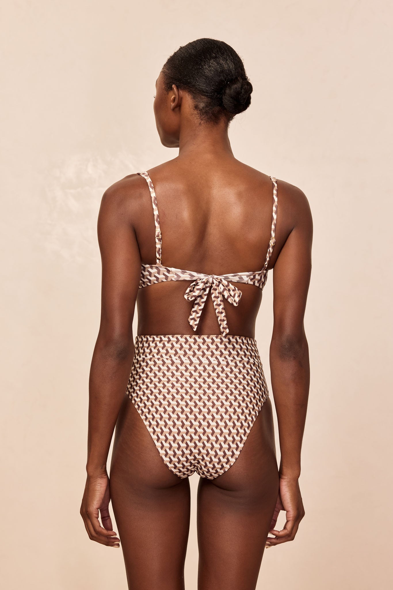 Rear view of model wearing high-waist brown-and-beige geometric-print bikini with tie-back top.