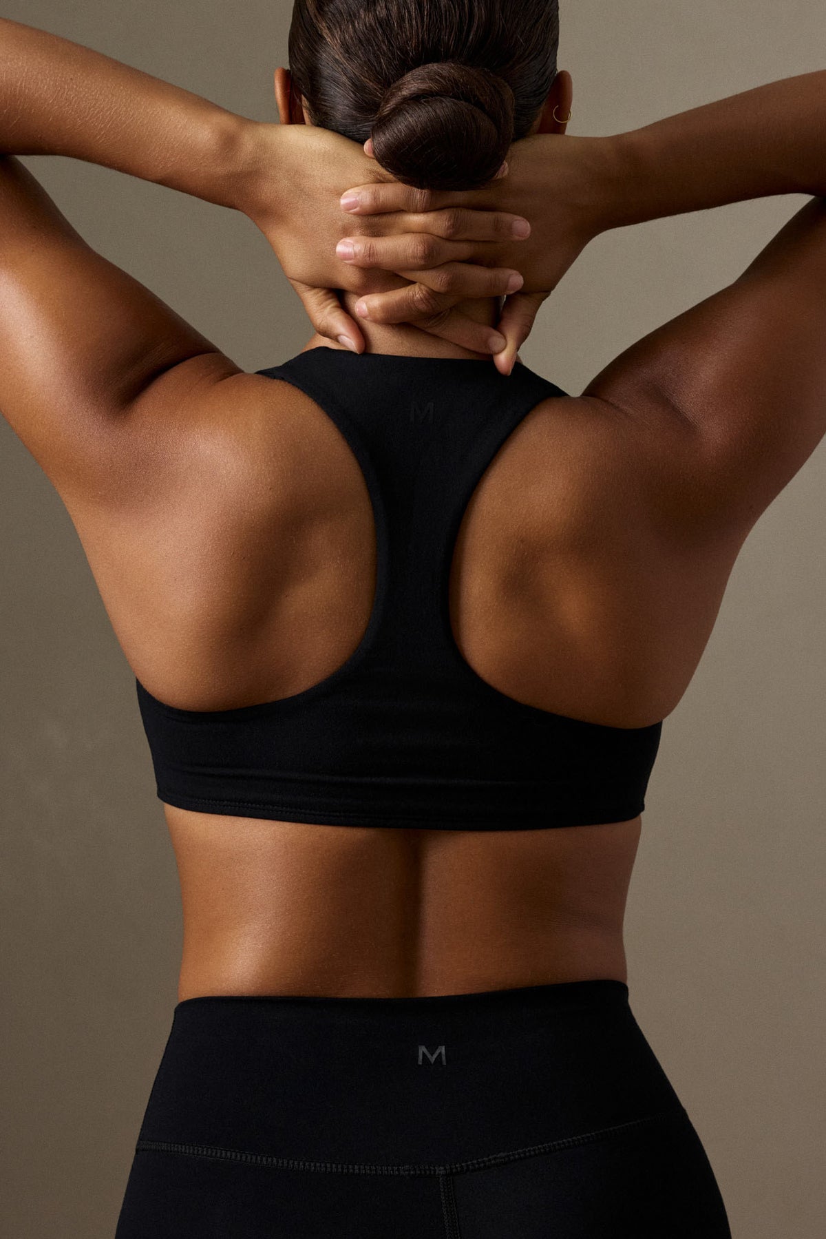 Back view of black Central Park Bra showcasing racer back and elastic underband on a model against a neutral background