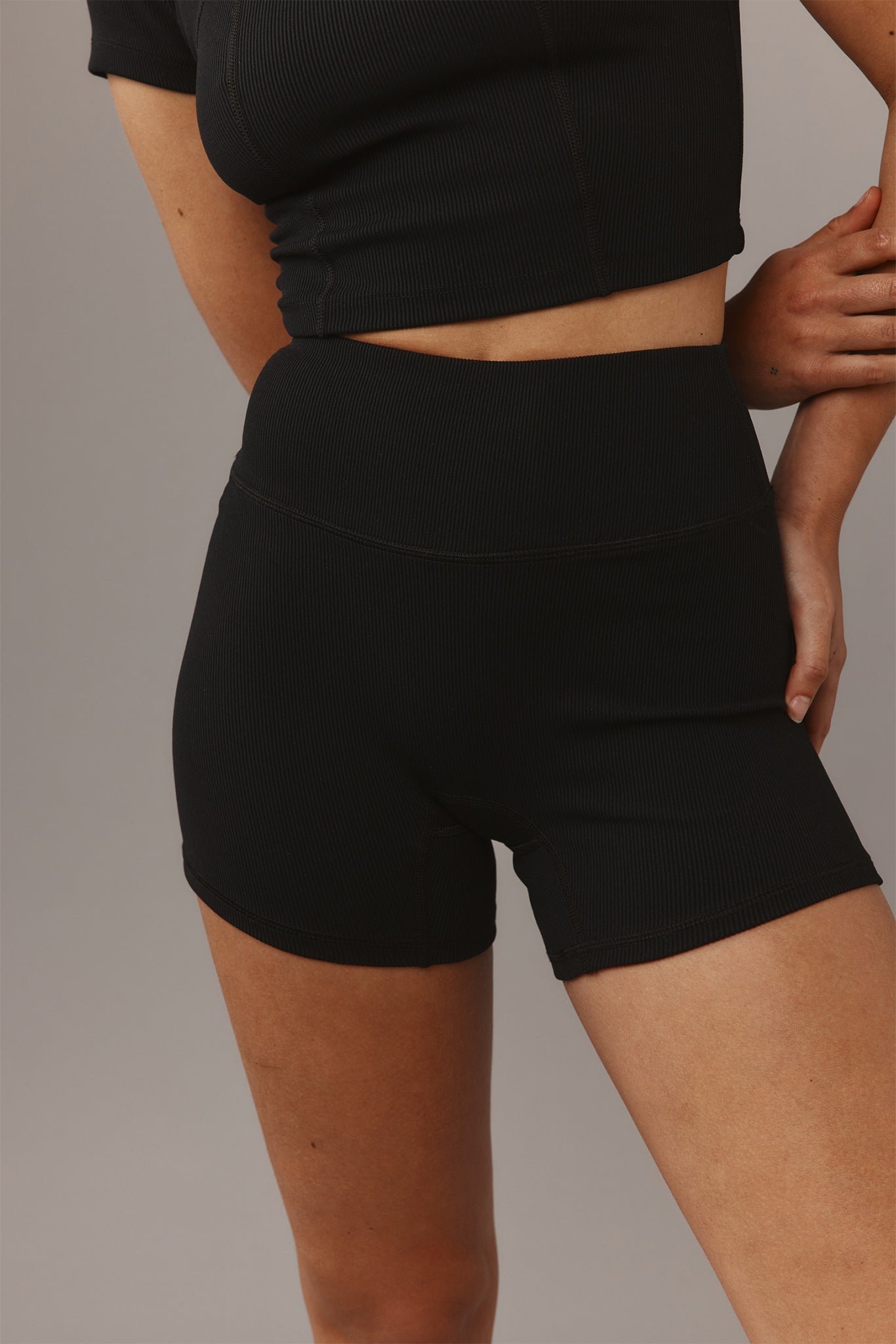 Black ribbed high-waist bike shorts and matching cropped top on model, close-up showing fit and seam details