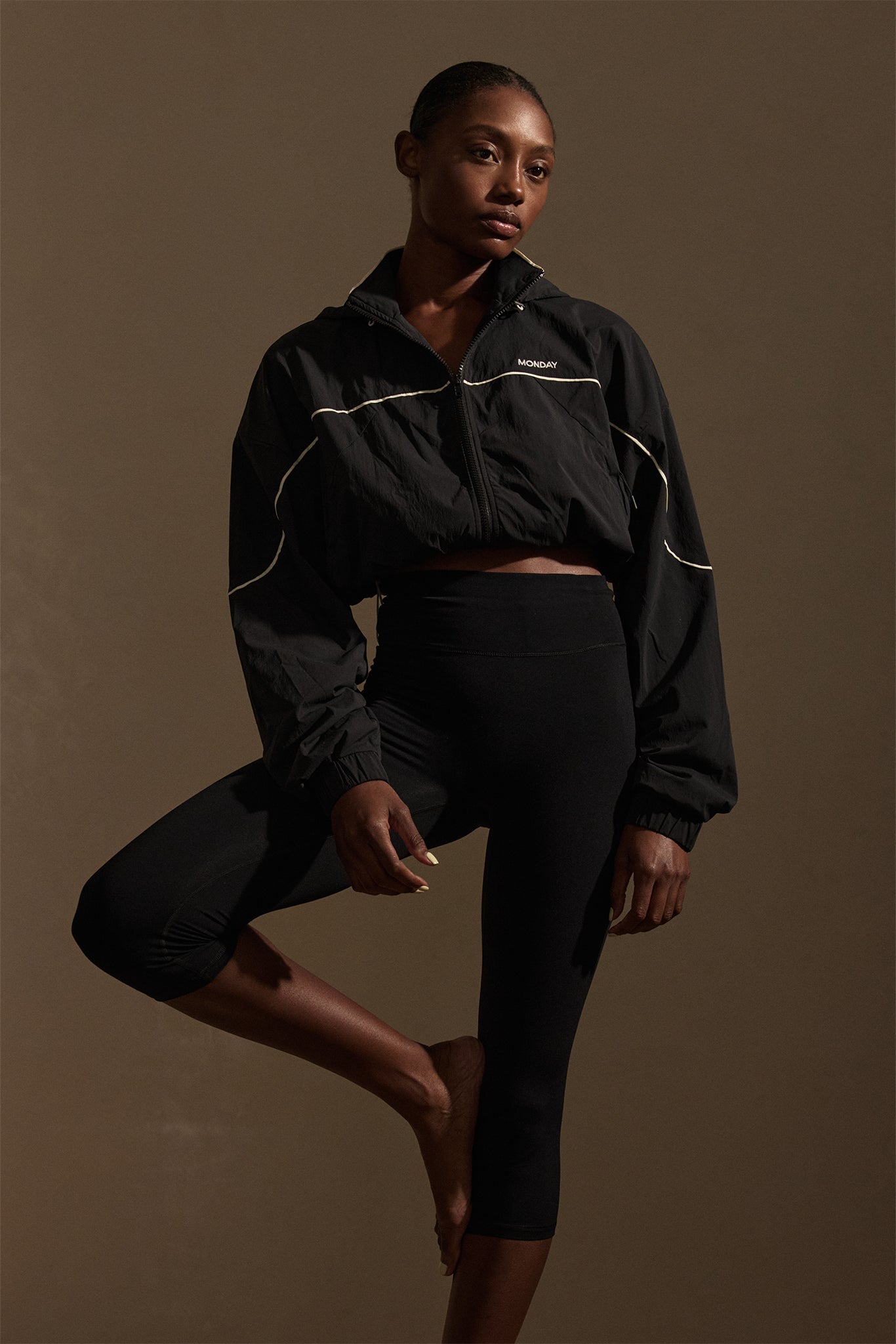 Three-quarter view of Acadia cropped legging in black jersey on model showing high-rise wide waistband and mid-calf length