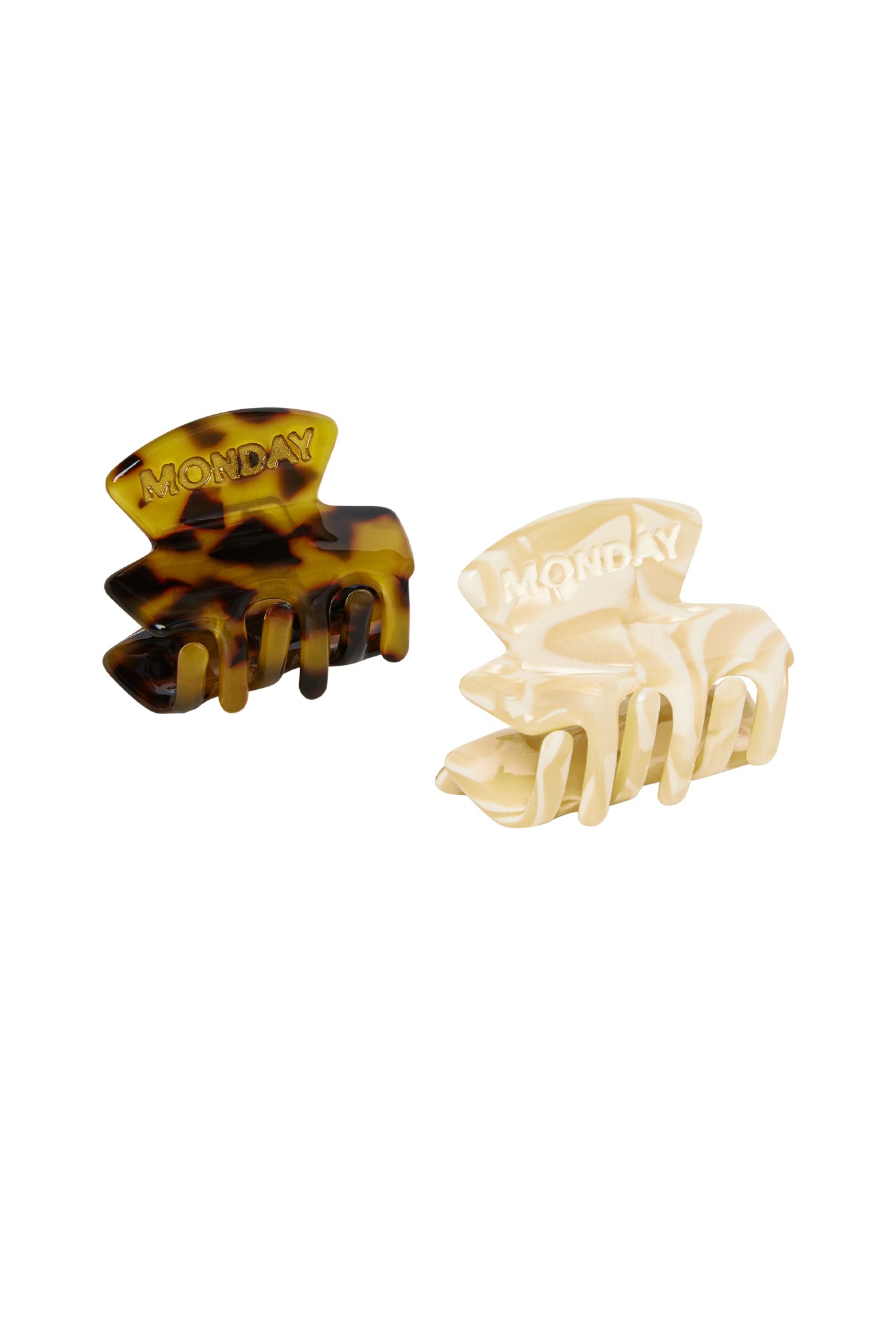 Two small hair claw clips — tortoiseshell and cream marbled finishes, each embossed with the word MONDAY.