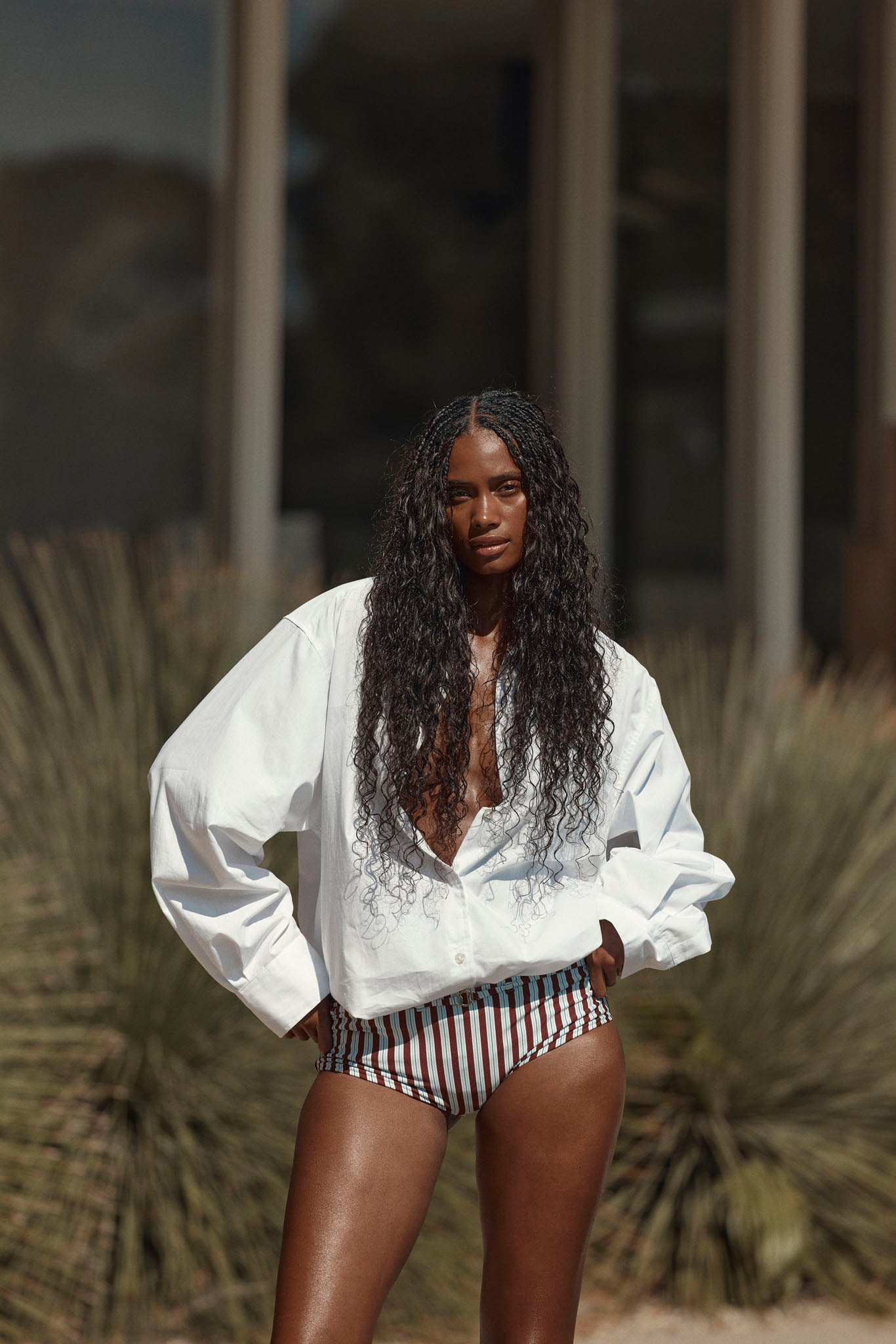 Model wearing burgundy striped bikini bottoms and a white shirt outdoors