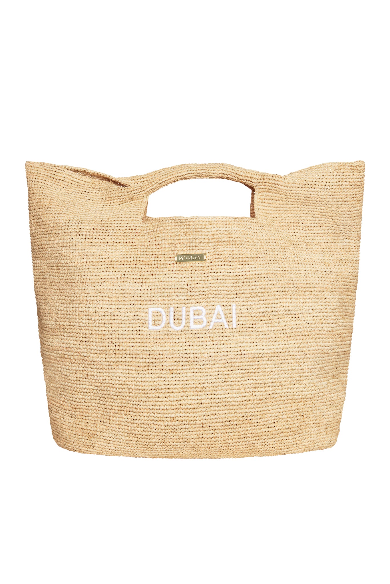 Beige woven straw tote bag with cutout handles, small 'MONDAY' plaque and 'DUBAI' embroidered on the front.