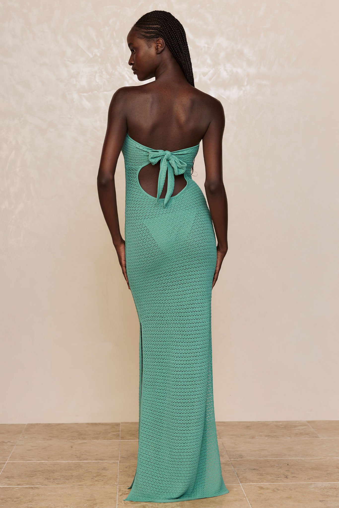 Model wearing mint-green crochet strapless gown with back cutout and tied bow, shown from the back